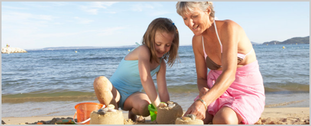 Granddaughter (7-9) building sandcastles with grandmother at beach